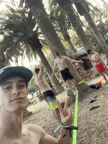 a man giving a peace sign in front of a slack line