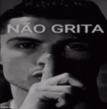 a man is holding his finger to his mouth in a black and white photo with the words `` não grita '' written above him .