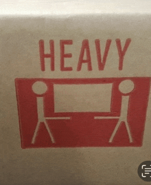 a cardboard box with two stick figures and the word heavy written on it