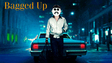 a man with a mustache and sunglasses is standing in front of a car with the words " bagged up " on the bottom