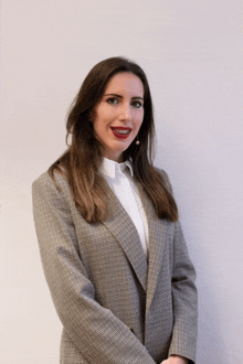 a woman in a plaid jacket and white shirt poses for a picture