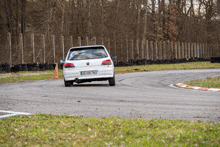 a white car with license plate 09-598-tnj is driving on a track