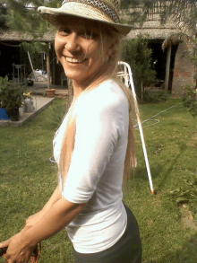 a woman wearing a straw hat is smiling in a garden