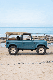 a blue jeep with a canopy is parked on a sandy beach