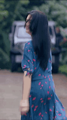 a woman in a blue floral dress is walking down a road .