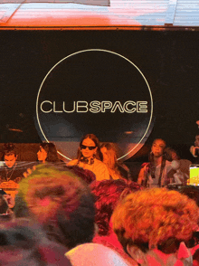 a crowd of people are gathered in front of a clubspace sign