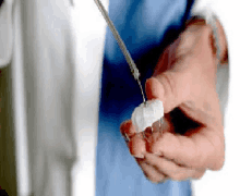 a close up of a person holding a syringe and a small object