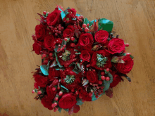 a heart shaped arrangement of red roses and berries