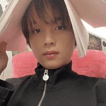 a close up of a person holding a book over their head with a pink pillow in the background