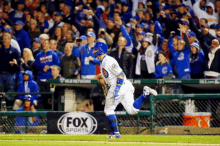 a baseball player is running on the field with a fox sports banner in the background