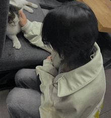 a person petting a cat while wearing a jacket that says ' a ' on it