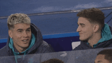 two young men wearing nike jackets are sitting next to each other and smiling