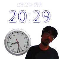 a man stands next to a clock that says 20:29 pm