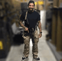 a man in a black shirt and camo pants holds a gun