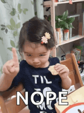 a little girl wearing a shirt that says " til nope " is giving a thumbs up