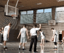 a group of men are playing basketball in a gym and one of them has the number 15 on his shirt