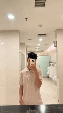 a young man taking a selfie in a public restroom