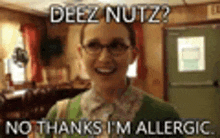 a woman wearing glasses and a green sweater is smiling and says deez nuts ? no thanks i m allergic .