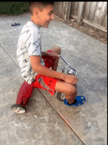 a boy wearing a shirt that says champion is riding a red toy car