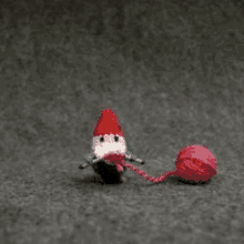 a crocheted gnome is holding a ball of yarn .