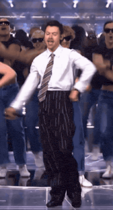 a man in a suit and tie is dancing with a group of people