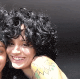 a woman with curly hair has a tattoo on her shoulder