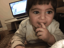 a little boy is eating something in front of a tv which shows a news report