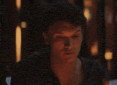 a man is sitting at a table in a dark room with candles in the background .
