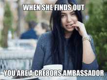 a woman is sitting at a table with a meme that says when she finds out you are a cre8ors ambassador