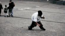 a man in a white shirt is running on a street while a group of people walk behind him .