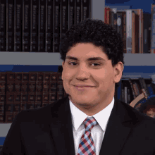 a man in a suit and tie is smiling in front of a bookshelf with a book titled " a dictionary " on it