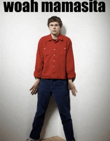 a man in a red shirt is standing in front of a white wall with the words woah mamasita written above him