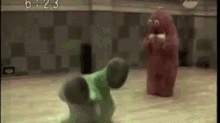 a green monster and a red monster are fighting in a room .