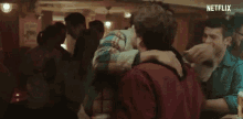 a group of men are hugging in a bar .