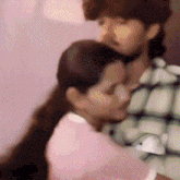 a woman in a pink shirt is hugging a man in a black and white plaid shirt .