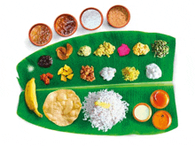 a banana leaf with a variety of food on it .