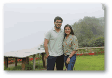 a man and a woman are posing for a picture in a field