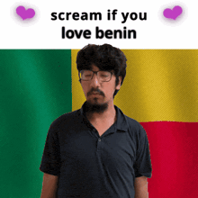 a man with glasses and a beard is standing in front of a benin flag and says scream if you love benin