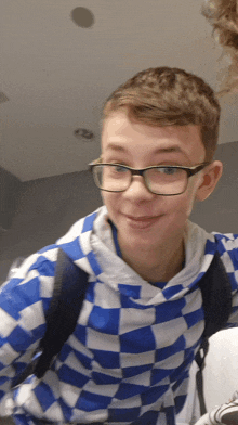 a young boy wearing glasses and a blue and white checkered sweatshirt