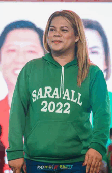 a woman wearing a green hoodie that says sara all 2022 on it