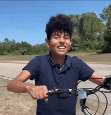 a young man in a blue shirt is riding a bicycle .