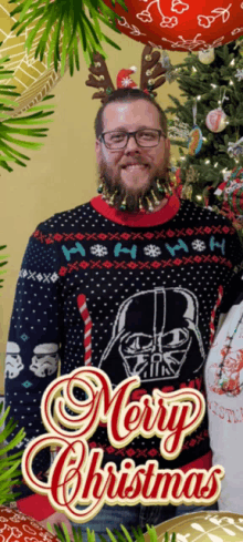 a man wearing a darth vader sweater stands in front of a merry christmas card