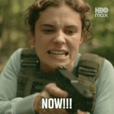 a woman is holding a gun with the word now written on her face