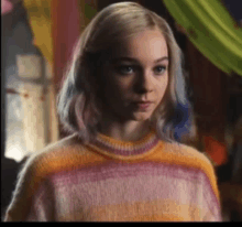 a woman with rainbow hair is wearing a colorful sweater .