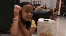 a little girl is brushing her hair in front of a polka dot bag with the word love on it