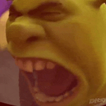 a close up of shrek 's face with his mouth open and teeth showing .