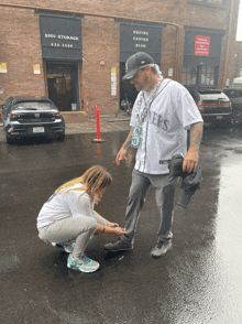 a man wearing a seahawks jersey is helping a little girl