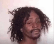 a man with curly hair and a beard is making a face .