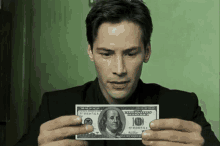 a man in a suit is holding a 20 dollar bill with franklin on it