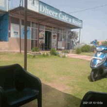 a blue scooter is parked in front of a restaurant called dheer cafe and resort